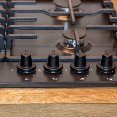 The control panel of the gas hob, the knob for adjusting the intensity of combustion of the gas stove burner. Black gas hob integrated into the wooden worktop
