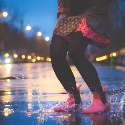 Low Section Of Woman Splashing Water On Street During Rainy Season