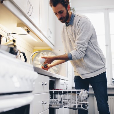 Man cleaning utensils in kitchen at home