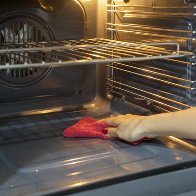 Cropped Hand Of Woman Cleaning Oven