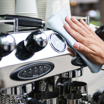 Man cleaning espresso machine after working day