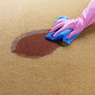 Gloved hand cleaning a wet spot on floor