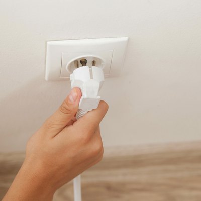Hand plugging in or out an electric cord into a socket