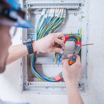 Close-Up Of Man Cutting Cables Against Wall