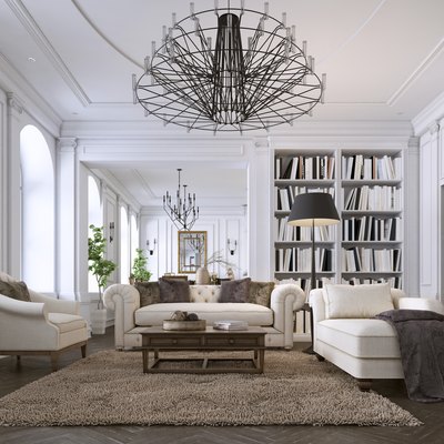 Luxury classic interior of living room and dining room with white furniture and metal chandeliers.