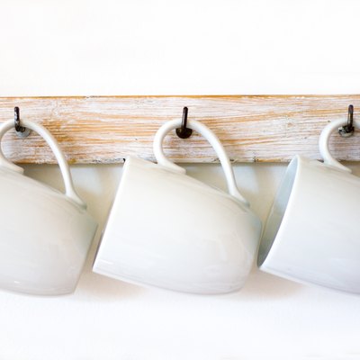 White Cups Hanging on Hooks, White Background, Copy Space
