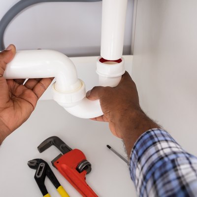Plumber Fitting Sink Pipe In Kitchen