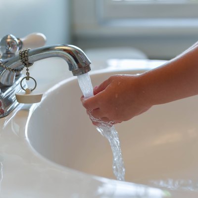 Closeup of child washing hands at bathroom sink - vertical