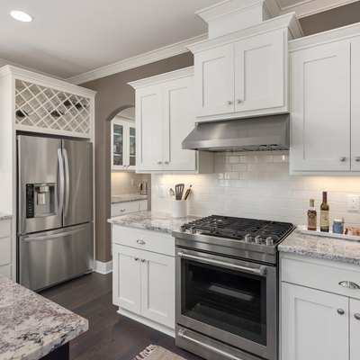 beautiful kitchen in new luxury home with island, stainless steel appliances, and hardwood floors.