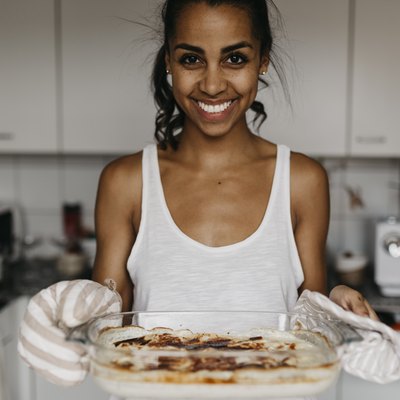 Portrait of smiling young woman with casserole in the kitchen