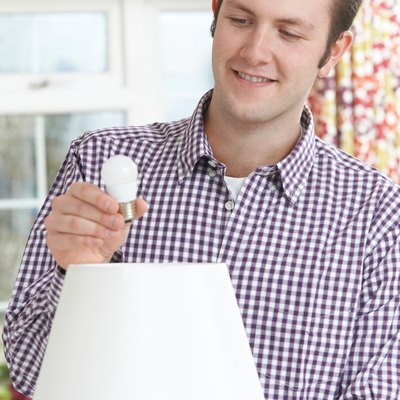Man putting LED lightbulb into lamp.