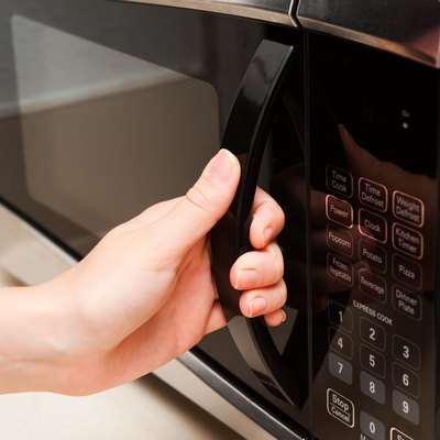 Hand holding microwave door close up