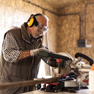 Mature carpenter using circular saw in his workshop