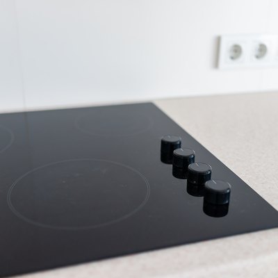 Closeup and knobs on modern luxury electric cook stove top stovetop cooktop with glass reflection and circles background in empty home
