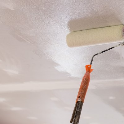 Workers are using paint roller on the ceiling