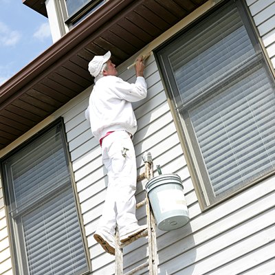 House Painter On Ladder Leaning Against House