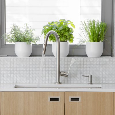 Modern kitchen stainless steel faucet with water running into sink.