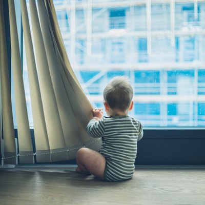 LIttle baby playing with curtain in apartment