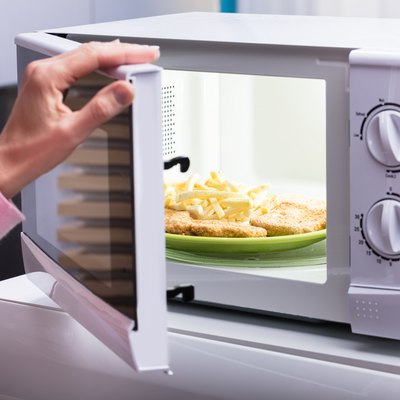 Woman Heating Fried Food In Microwave Oven