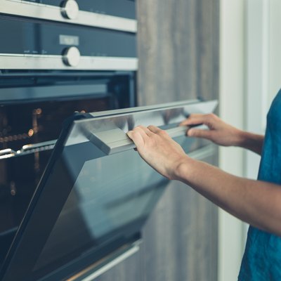 Young woman opening the oven