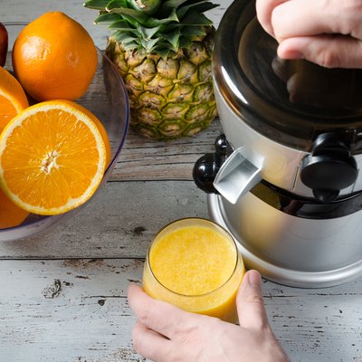 Man preparing fresh orange juice. Fruits in background