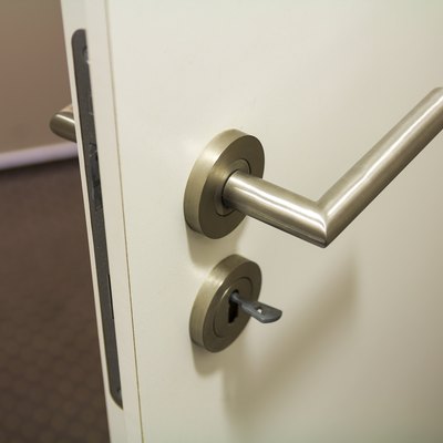 Close up of slightly open new white plastic door with bright shiny handle and keys in the lock. Safety and security of house, office.