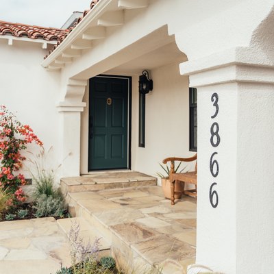 A white Mediterranean-style home entrance with black address numbers