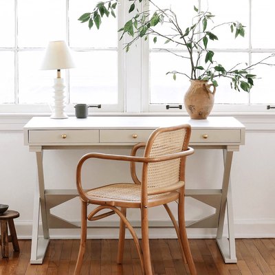 Home office desk painted with light gray milk paint in front of window with lamp and vase