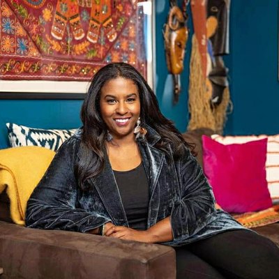 Seana Freeman on brown couch with colorful pillows and tribal wall hangings