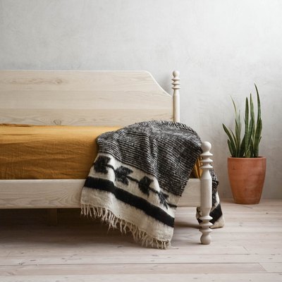 light wood eco-friendly bed frame with mustard bedding in a gray room