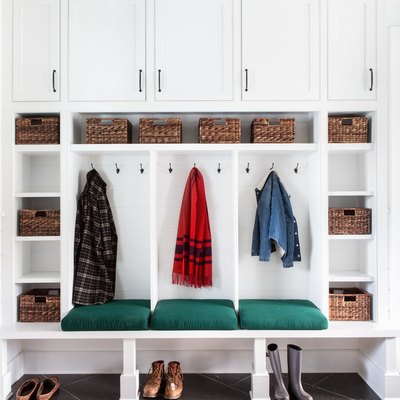 mudroom storage with white cabinets, slate floor and eclectic rug