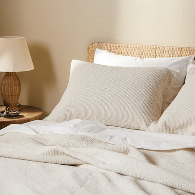 cream bedding with natural woven headboard and bedside table