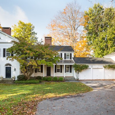 white garage door on colonial home surrounded by trees