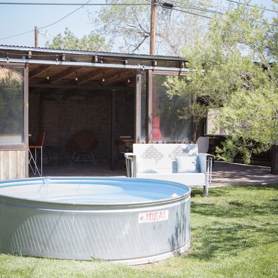 A stock tank pool sitting in front of a garden shed