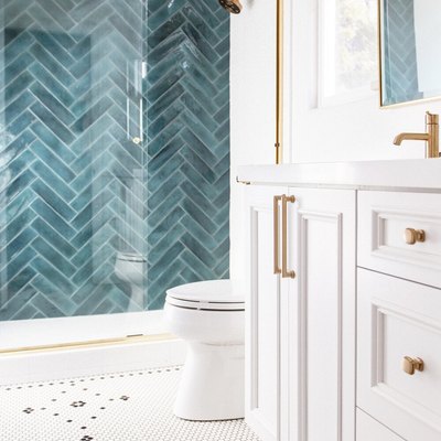 white bathroom with teal shower tile wall and brass hardward plus mosaic tile floor