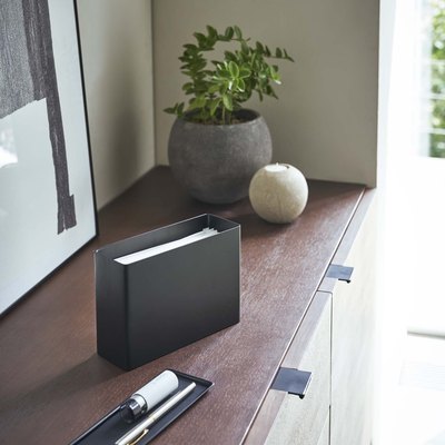 face mask dispenser on wooden furniture with plants nearby