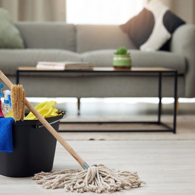 Shot of a mop and bucket of cleaning supplies on living room floor.