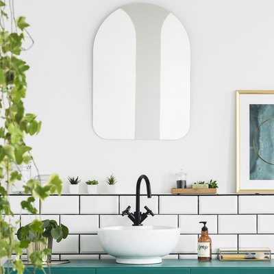 Mirror and poster in white bathroom interior with washbasin and plant. Real photo.