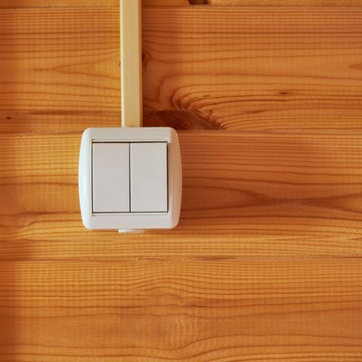 Double white plastic light switch on wooded wall. Electric equipment of house. Close up view with copy space for the text.