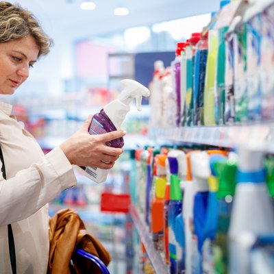 Woman shopping for cleaning products at supermarket.