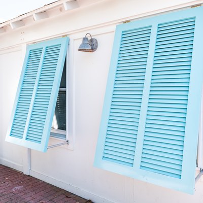Pastel turquoise blue colorful hurricane window shutters closeup architecture open exterior of house in Florida beach home during sunny day, painted