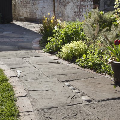 Paving of reclaimed limestone, bricks and cobbles in a domestic garden.