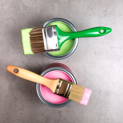 Paintbrushes on cans of green and pink paint.