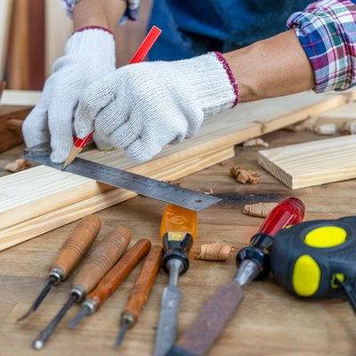 Carpenter working, hammer, ruler, and screwdriver on construction background.