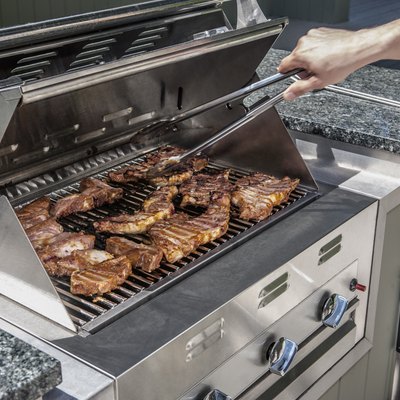 outdoor propane gas grill with man turning stakes