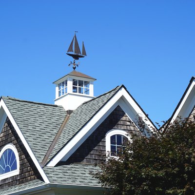 Iconic sailing ship weather vane mounted atop a white cupola on a classic gabled New England rooftop