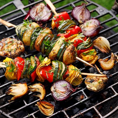 Vegetarian skewers, grilled vegetable skewers of zucchini, peppers and potatoes with the addition of aromatic herbs and olive oil on the grill outdoors.