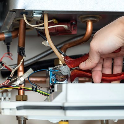 Technician repairing the combi gas boiler with wire cutter in hand