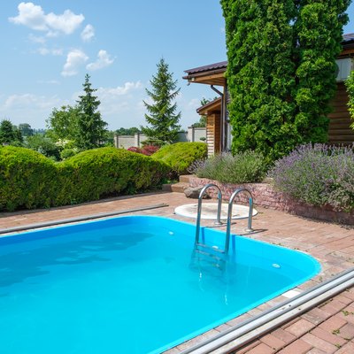 Swimming pool and garden with nicely trimmed bushes and stones in backyard.
