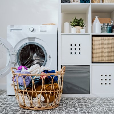 Closeup of clothes in basket, open washing machine standing in background, weekend cleaning, household chores, laundry room.